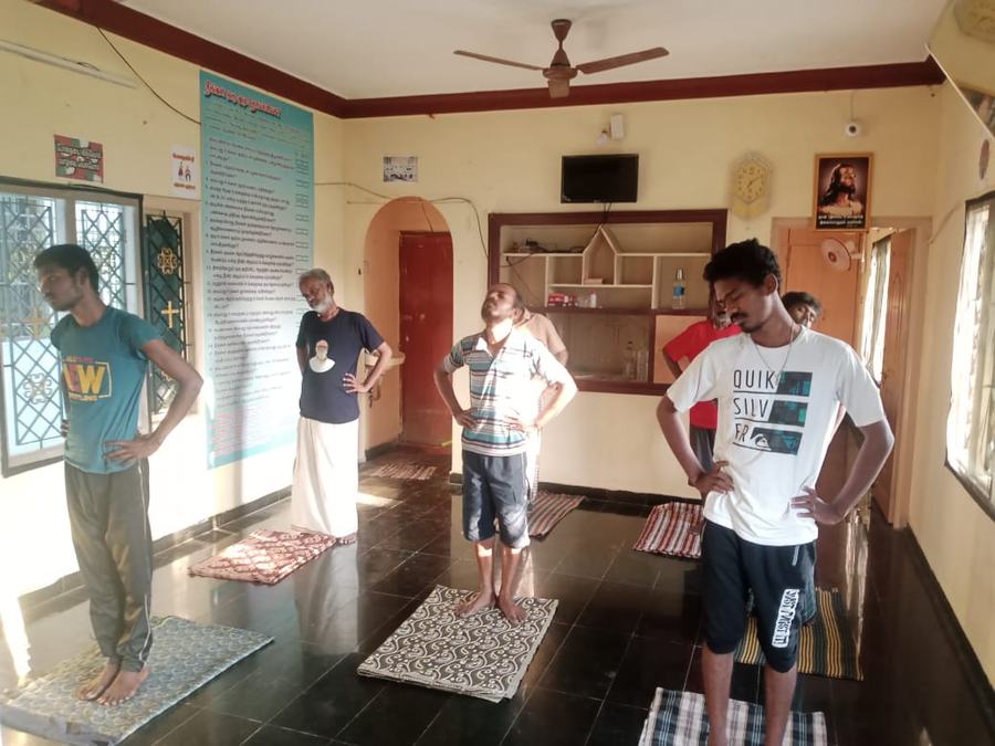 Residents at a standing posture during the morning yoga session at Dunamis, Madurai